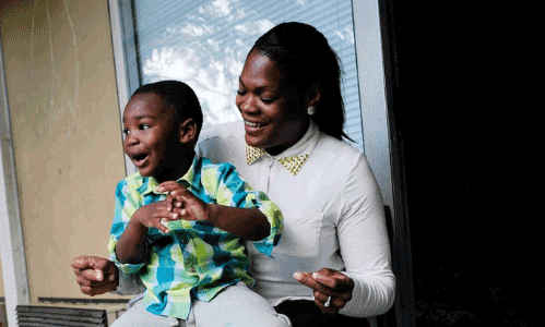 smiling black woman holding young black boy on her lap